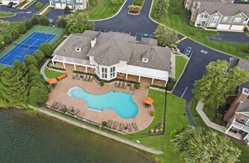 A mansion with an aerial view of a swimming pool and tennis court